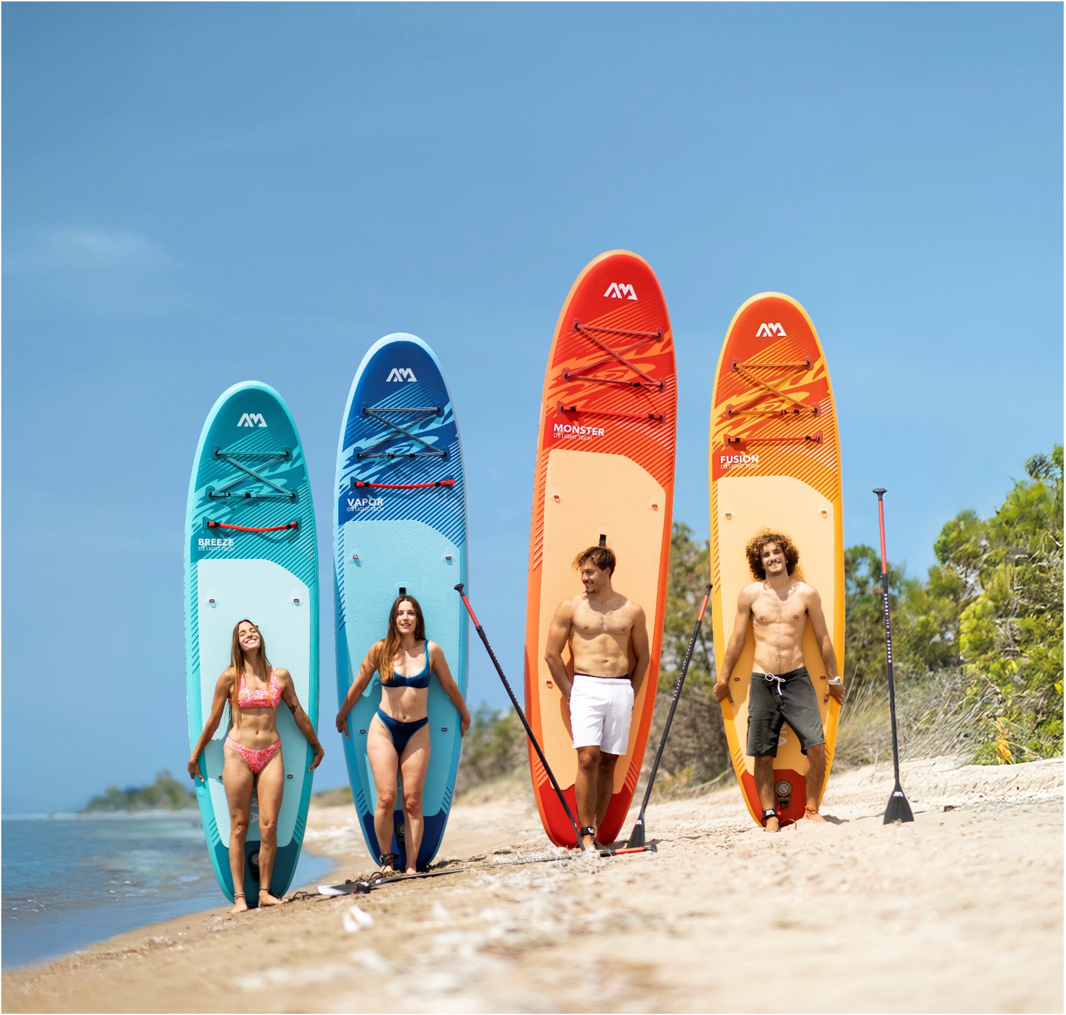 Patru persoane pe plajă cu plăci de stand-up paddle Aqua Marina